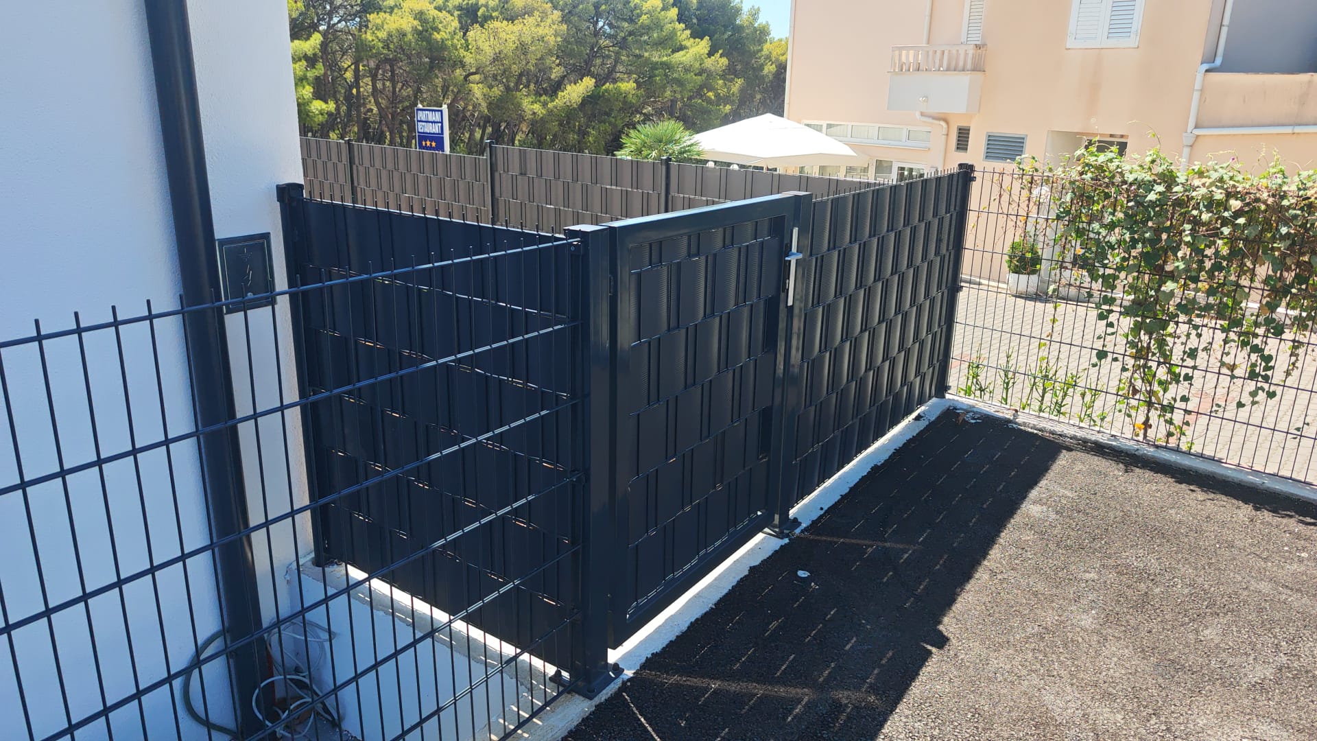 Antracit panel ograda s trakama i pješačka vrata na betonskom zidu