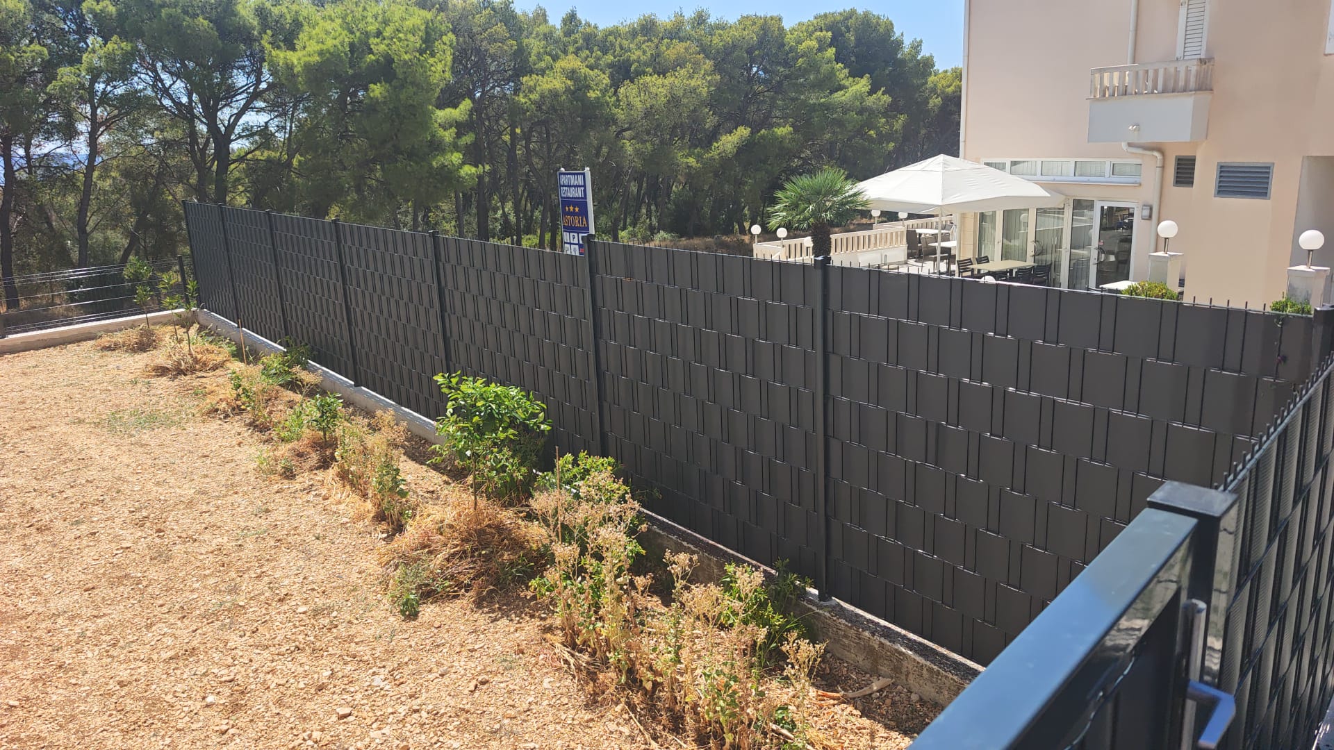 Antracit panel ograda s trakama na betonskom zidiću uz borovu šumu